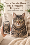 Custom cat photo pillow on a neutral sofa beside a phone showing the original cat photo, with the headline Turn a Favorite Photo Into a Huggable Keepsake.
