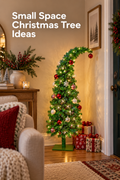 Vertical holiday interior showing a slim green Christmas tree with a curved top tucked into a narrow corner beside a dark entry door. The tree glows with warm white lights and is decorated with red, white, and striped ornaments above a flat green stand, with wrapped presents at the base. A wood console holds greenery, berries, books, a candle, and a small tree, while part of a cozy chair and rug appear in front. White headline text reads “Small Space Christmas Tree Ideas.”