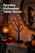 Vertical Halloween lifestyle scene showing a black glittered tabletop tree glowing with orange branch-tip lights on a rustic wood console. A lit black jack-o’-lantern, orange pumpkins, a glass candle, autumn foliage, stacked dark books, black gauze, and a small black crow surround the tree beneath a large round mirror. Warm amber lighting creates a cozy spooky entryway display. White headline text at the upper left reads “Spooky Halloween Table Decor.”